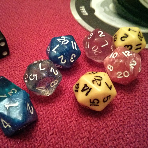 Six coloured 20-sided dice on a red table cloth.